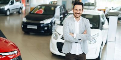 Autohändler steht vor Autos im Autohaus