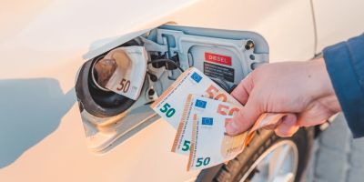 Mann legt Geld in einen Autotank