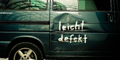Ein grüner Kleinbus hat eine Delle auf der rechten
