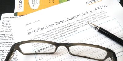 Ein Schufa-Formular liegt auf dem Schreibtisch, darauf befindet