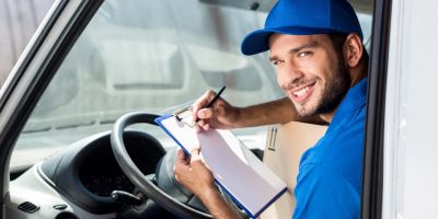 Mitarbeiter eines Lieferservices sitzt in seinem Fahrzeug und