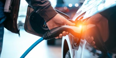 Ein Mann tankt ein Elektroauto.