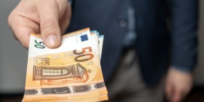 Mann im Anzug hat Geldscheine in der Hand und streckt seinen