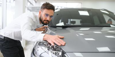Mitarbeiter prüft den Zustand des Lacks eines Fahrzeugs bei Rückgabe.