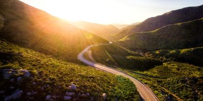 Eine Straße führt durch eine grüne Berglandschaft.