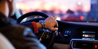 Ein Mann sitzt am Abend in einem Auto und lenkt das Fahrzeug