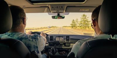 Zwei Personen sitzen im Auto und fahren über eine Bundesstrasse.